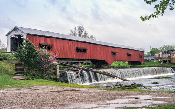 Old covered bridge over a roaring waterfall 