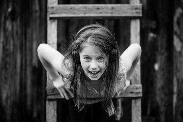 Little girl enjoy music with headphones outdoors. Black and white photo.