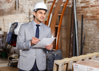 Confident male architect in suit and helmet controlling process of building