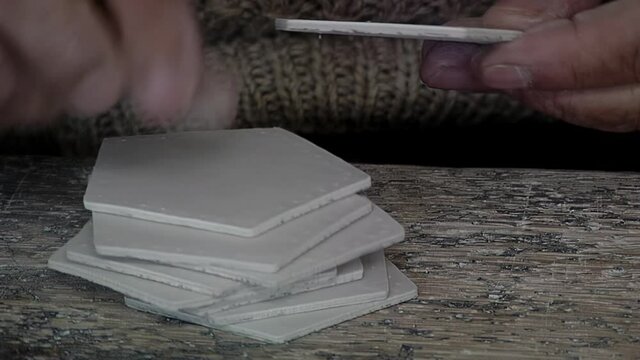 Hands of an Old Worker holding Pieces of Synthetic Leather at Football Factory.
