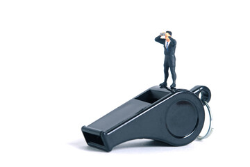 Businessmen using binoculars standing above black whistle. Miniature tiny people toys photography....