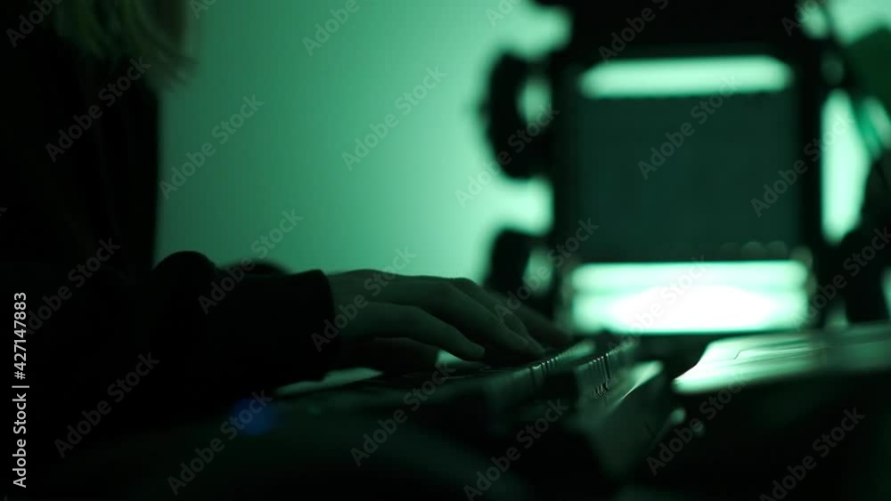 Poster a criminal hackergirl with black hood using laptop and big computers to hack network system from her