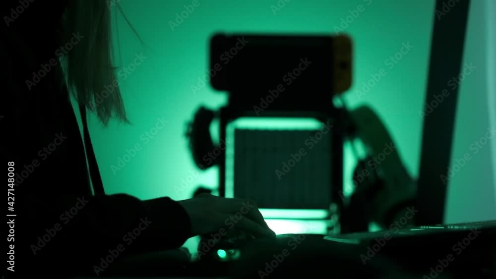Poster a criminal hackergirl with black hood using laptop and big computers to hack network system from her