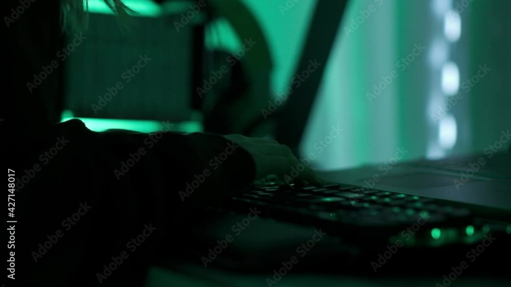 Poster a criminal hackergirl with black hood using laptop and big computers to hack network system from her