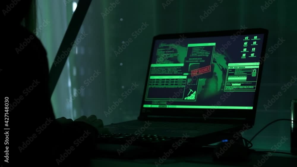 Poster a criminal hackergirl with black hood using laptop and big computers to hack network system from her