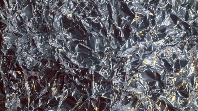 Background from foil of silver and golden color is shimmering of bright lights. Macro. Closeup
