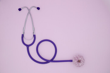 Stethoscope and pink flower on a pink background with copy space. Medical flat lay.