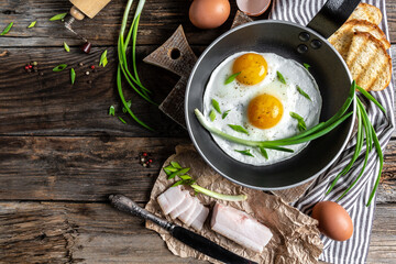 Traditional Ukrainian or belorussian food. Breakfast, lunch bacon, lard fried eggs and toast on old wooden table. banner, catering menu recipe place for text, top view
