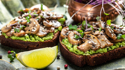 Toast avocado, mushrooms and microgreen whole grain sandwich. Decorated with sesame. Vegetarian food. Vegan menu. Food recipe background