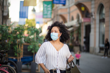 Woman with protective mask on face walking trough city.