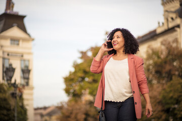 Business woman standing on street and talking on phone.