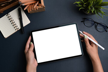 Top view of female holding mock up digital tablet with empty screen and stylus pen on dark blue...