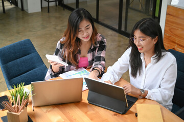 Two young asian creative designer working together in co working space.