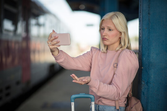 Woman waiting on train station using smart phone.