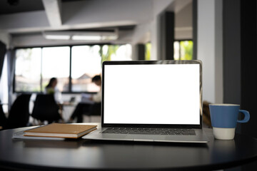 Close up view of computer laptop with blank screen, coffee cup and notebook on black office desk.