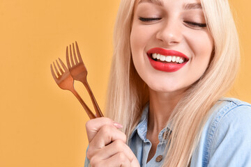 Beautiful young woman with forks on color background, closeup