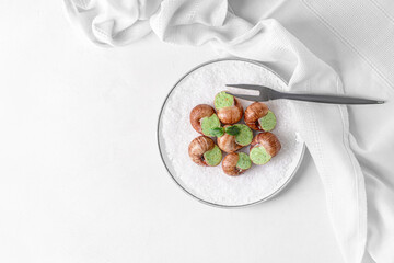 Plate with tasty snails on light background