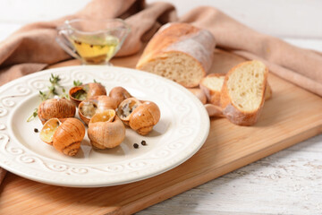 Plate with tasty snails on wooden background