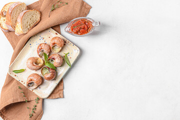 Plate with tasty snails on light background