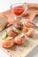 Plate with tasty snails on light background, closeup