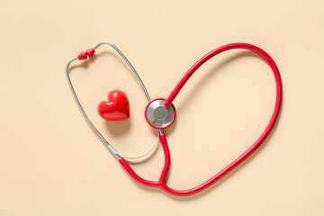 Modern stethoscope and heart on color background