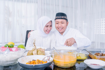 Happy Muslim couple look at foods in dining table