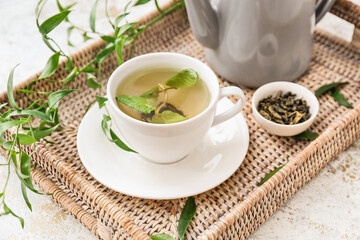Wicker tray with cup of green tea on table