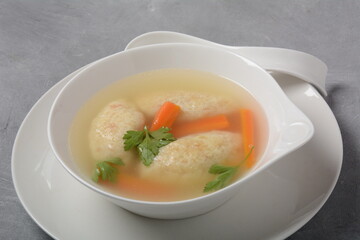 Griessnockerlsuppe. Clear Soup with Semolina Dumplings in a white bowl. German food.  Bavarian cuisine.
