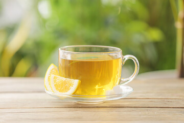 Cup of green tea with lemon on table outdoors