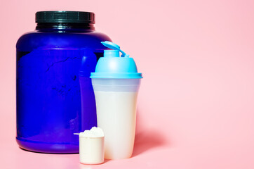 Jar of protein and shaker on pink background with copy space.