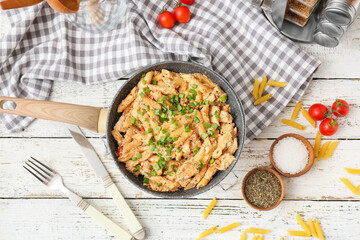 Frying pan with tasty cajun chicken pasta on white wooden background
