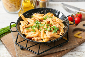 Frying pan with tasty cajun chicken pasta on table