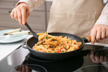 Woman cooking cajun chicken pasta in kitchen