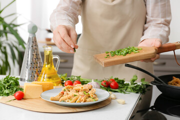 Obraz na płótnie Canvas Woman cooking cajun chicken pasta in kitchen