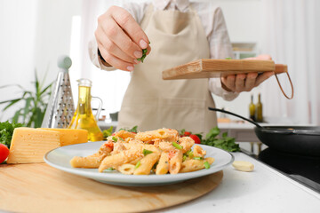 Woman cooking cajun chicken pasta in kitchen