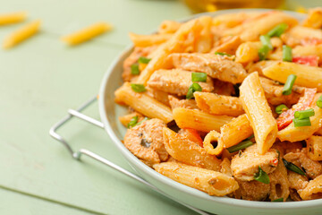 Plate with cajun chicken pasta on color wooden background, closeup