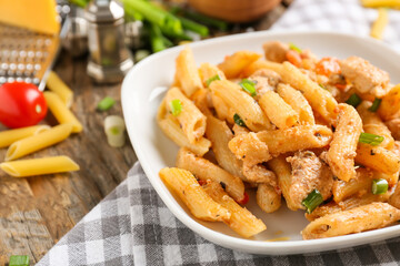 Plate with cajun chicken pasta on wooden background