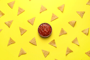 Bowl of tasty salsa sauce with nachos on color background
