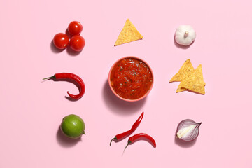 Bowl of tasty salsa sauce with ingredients on color background