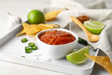 Tray with bowl of tasty salsa sauce and nachos on light background