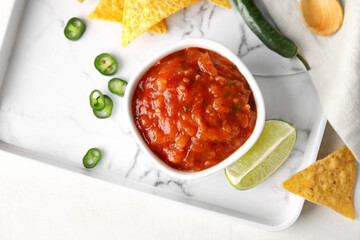 Tray with bowl of tasty salsa sauce and nachos on light background - obrazy, fototapety, plakaty