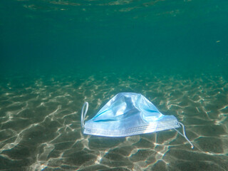 Pollution of the ocean with corona virus residues. A medical mask floats on the surface of the sea...
