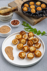 Suji appe or appam served on a appam pan with peanuts and tamarind chutney