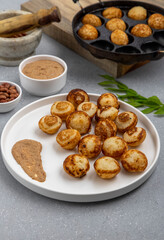 Suji appe or appam served on a appam pan with peanuts and tamarind chutney
