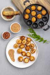 Suji appe or appam served on a appam pan with peanuts and tamarind chutney