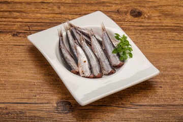 Anchovies in the bowl served basil leaves