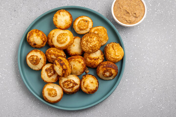 Suji appe or appam served on a appam pan with peanuts and tamarind chutney