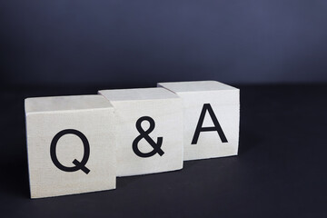 Word 'Q and A' on wooden blocks, cubes on a dark background.