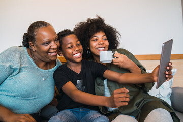 Grandmother, mother and son taking a selfie with digital tablet.