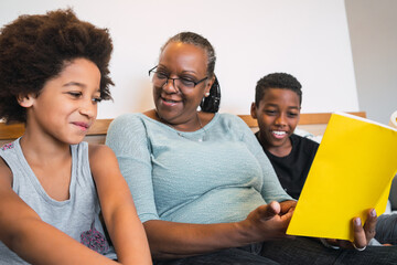 Grandmother reading a book to grandchildren.